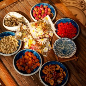 A variety of herbal tea ingredients beautifully arranged in ceramic bowls on a wooden table.