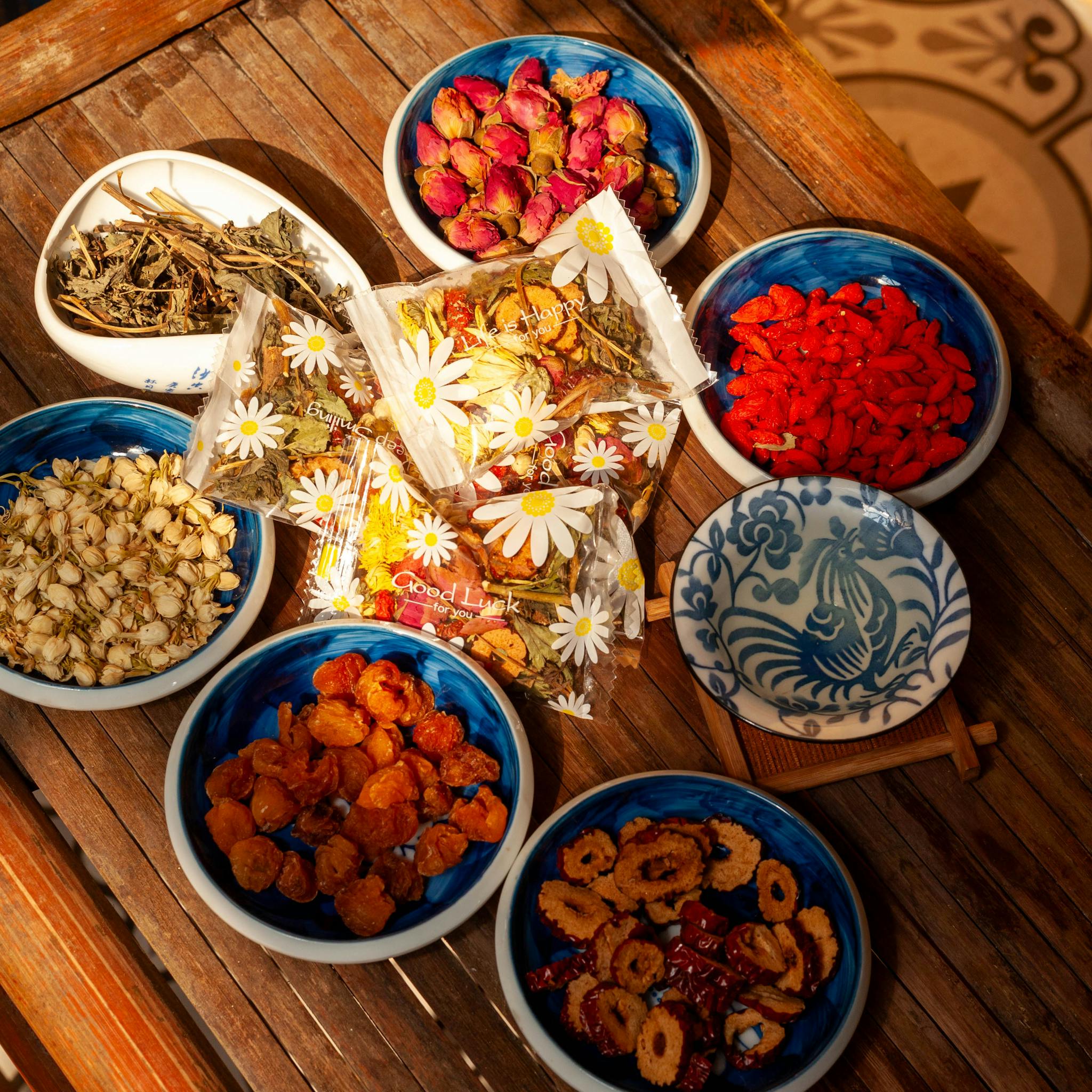 A variety of herbal tea ingredients beautifully arranged in ceramic bowls on a wooden table.