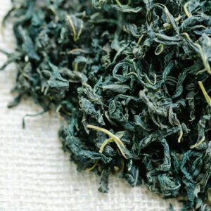 Detailed view of dried herbal tea leaves on burlap, perfect for health and wellness themes.